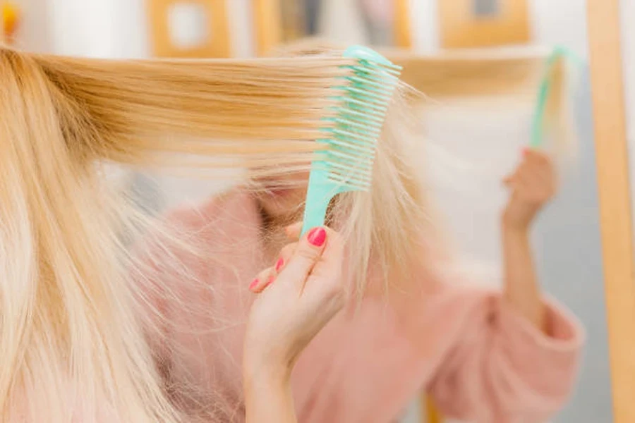 Donna che indossa una vestaglia che si spazzola i capelli