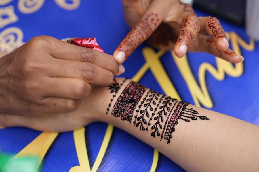 Woman applying henna tattoo on a tourist’s hand