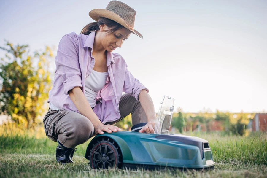 Une agricultrice inspecte sa tondeuse robotisée