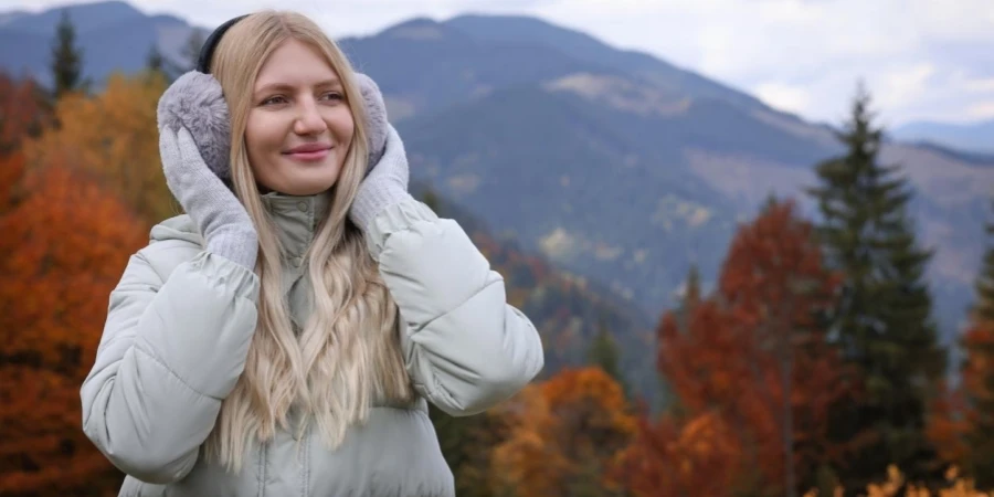 Young Beautiful Woman Wearing Warm Earmuffs in Mountains