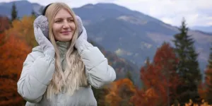 Giovane bella donna che indossa paraorecchie caldi in montagna