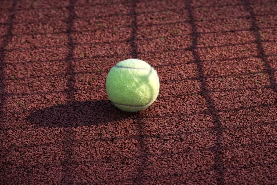 Yellow tennis ball is resting on a tennis hardcourt surface