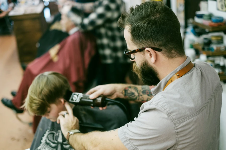 Pria mencukur rambut anak laki-lakinya