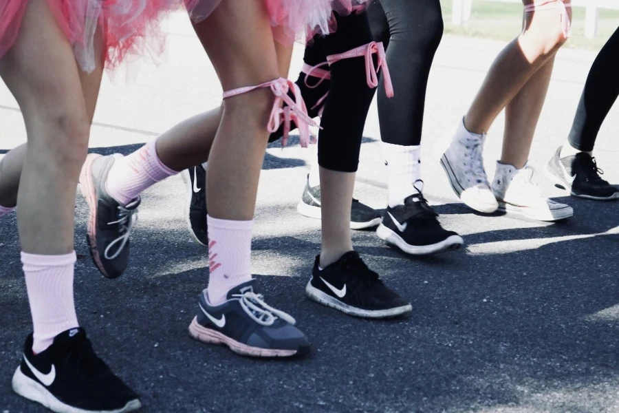 Person, die mehrere Paar Nike-Laufschuhe trägt und tagsüber auf grauem Betonboden steht