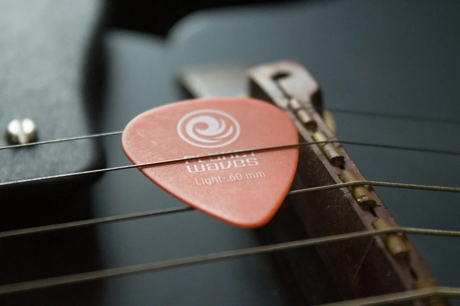 fotografia com foco seletivo de palheta de guitarra marrom em cordas de guitarra