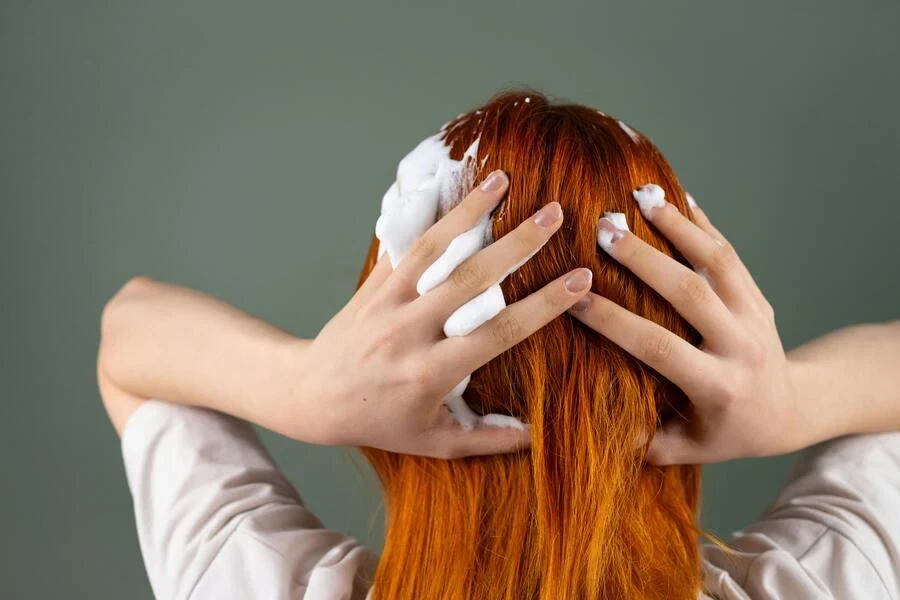 femme se lavant les cheveux avec de la mousse de shampoing