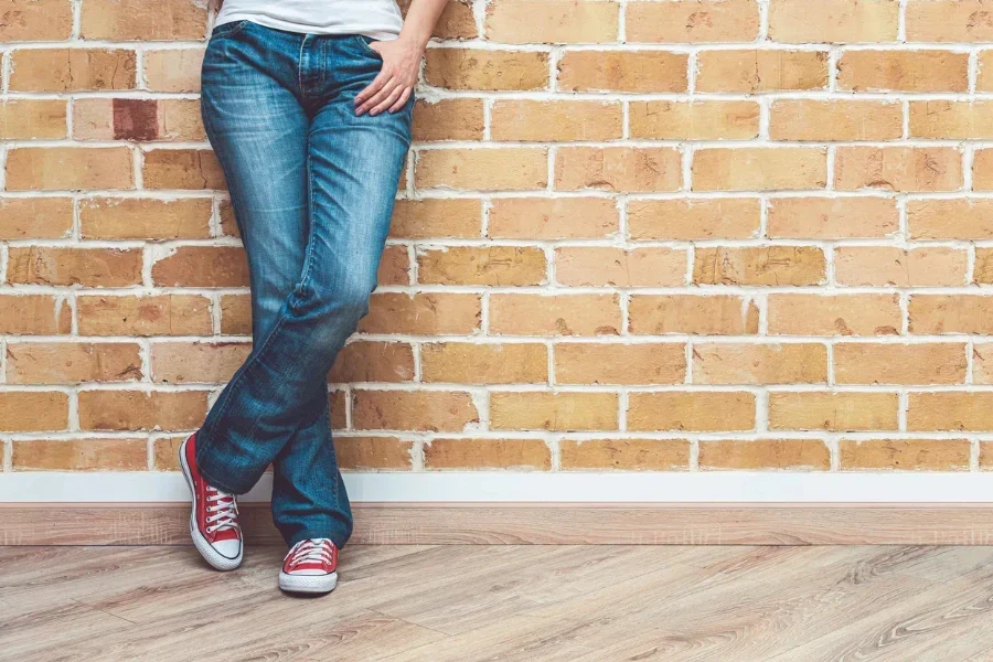 Piernas de mujer con jeans bootcut y zapatillas rojas