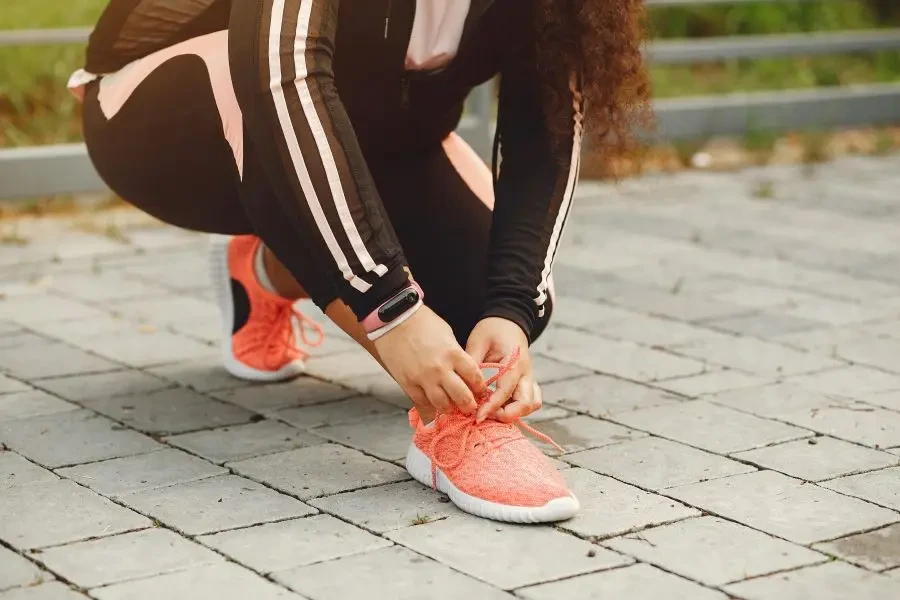 屋外での運動に備えて、レンガの歩道で靴ひもを結ぶ女性