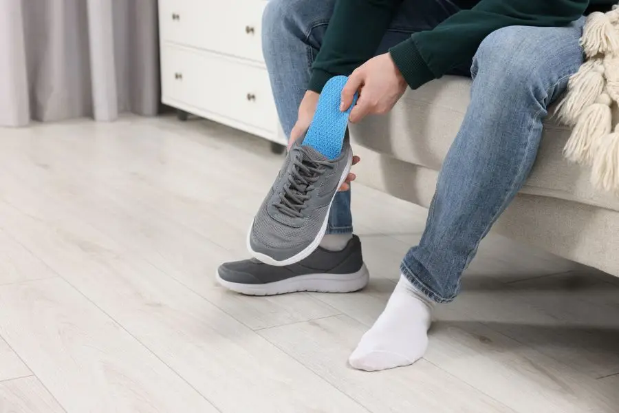 Man putting orthopedic insole into shoe