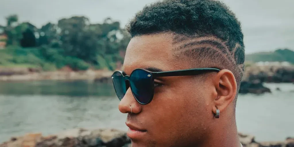 A beautiful shot of an attractive man with sunglasses with the rocks and the ocean in the background