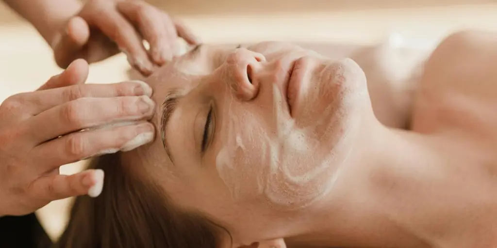 Gros plan d'une femme recevant un massage facial apaisant avec un masque de soin