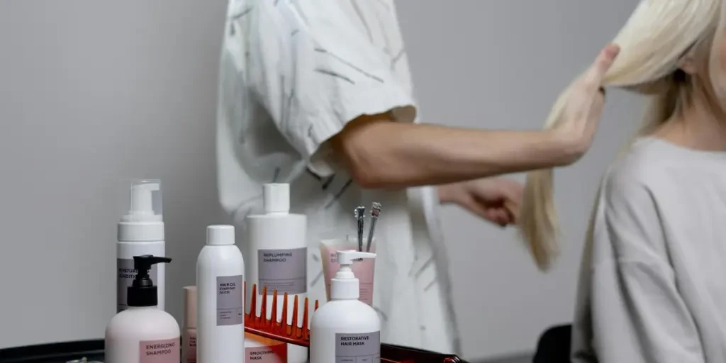 A hairdresser styling a blonde womans hair in a salon, showcasing hair care products on a table