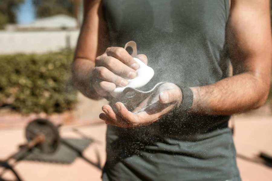A man applies chalk to his hands during an outdoor weightlifting session, emphasizing fitness