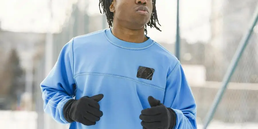 A man jogs outdoors in a blue long sleeve shirt during winter, promoting a healthy lifestyle