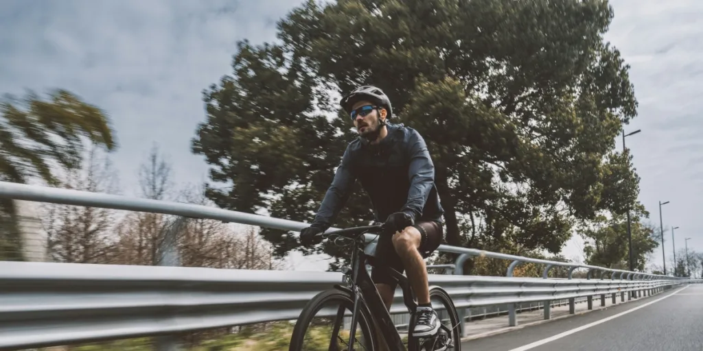 Un hombre conduce una bicicleta eléctrica de carretera rápidamente sobre la carretera de caucho.