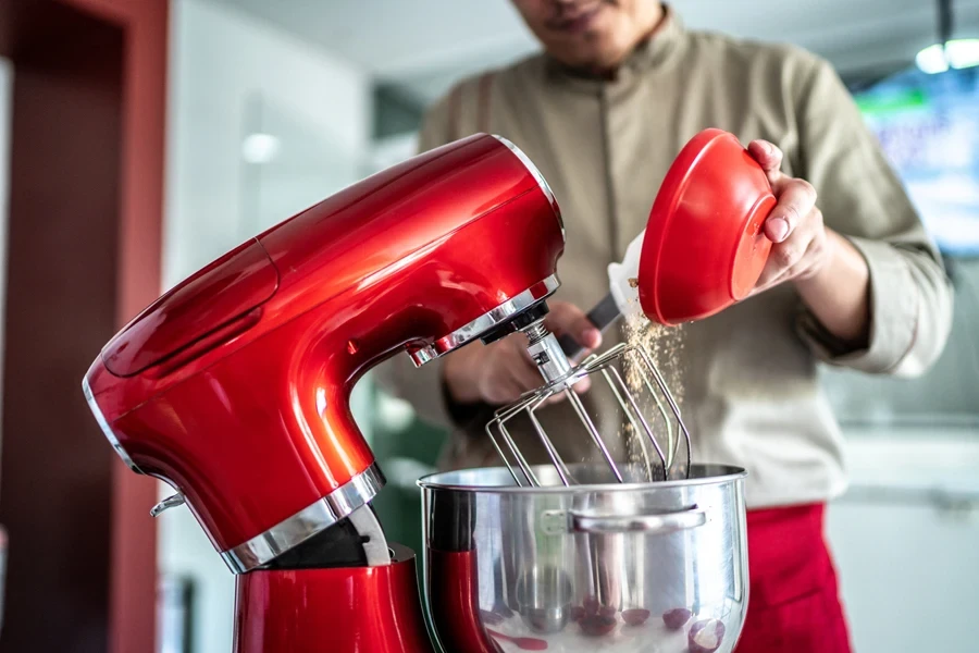 A man using a red tilt-head stand mixer