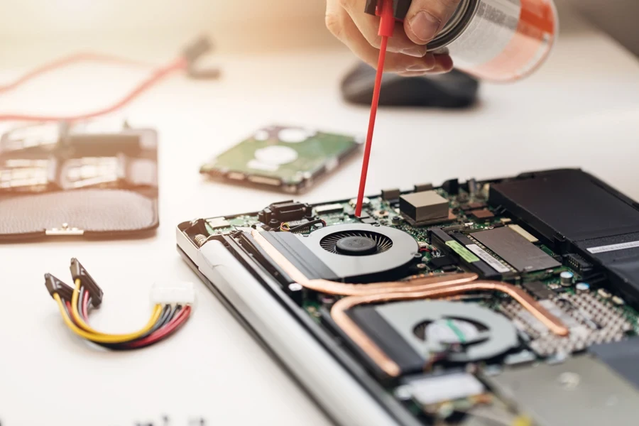 A mechanic cleaning laptop with compressed air duster