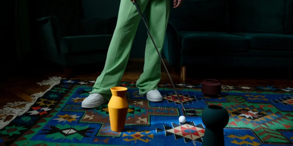 Een persoon in een groen pak speelt indoor golf op een kleurrijk tapijt