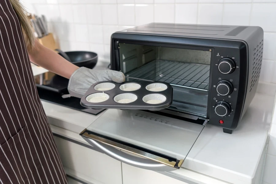 Una persona colocando una bandeja para muffins en un molde para muffins convencional.