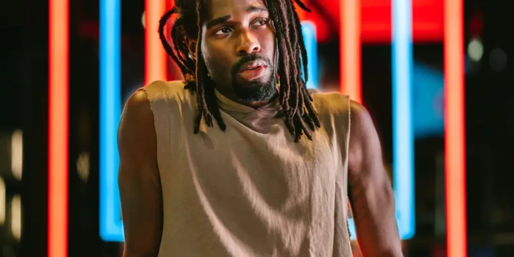 A portrait of a handsome black man in front of colorful neon lights