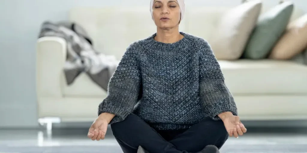 A senior woman who is battling caner, is seen in the comfort of her own home as she practices Yoga