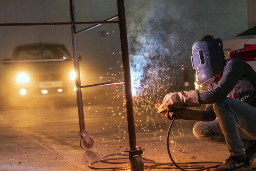 Um soldador trabalhando com faíscas voando em um ambiente industrial durante a noite por Nishant Aneja