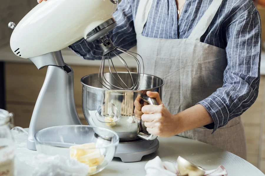 A woman using a stand mixer in her kitchen