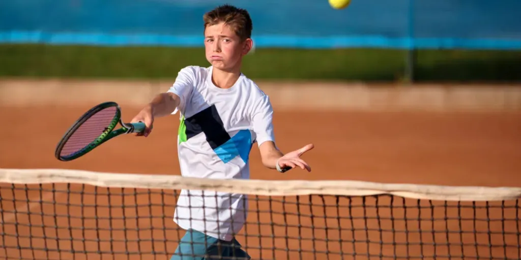 Ein junger Sportler im Alter von zwölf Jahren ist in ein Tennisspiel verwickelt