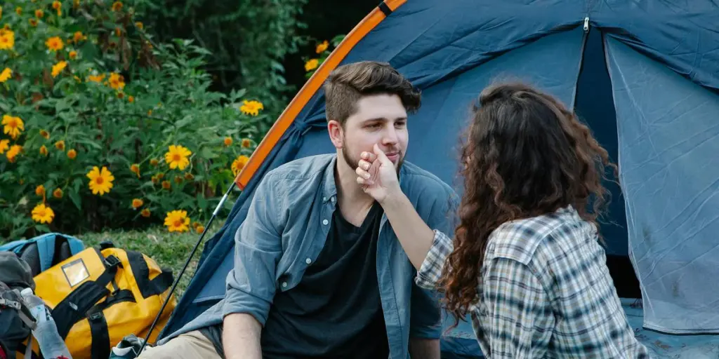 Een jong stel geniet van een romantische kampeerdate in de buitenlucht, omringd door de natuur en een levendige tent