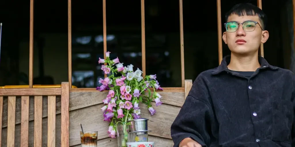 A young man enjoys a casual moment outdoors, sipping iced coffee and smoking