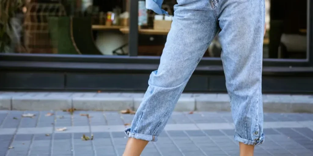 Beautiful fashionable young woman in sunglasses and jeans and jacket posing on the street