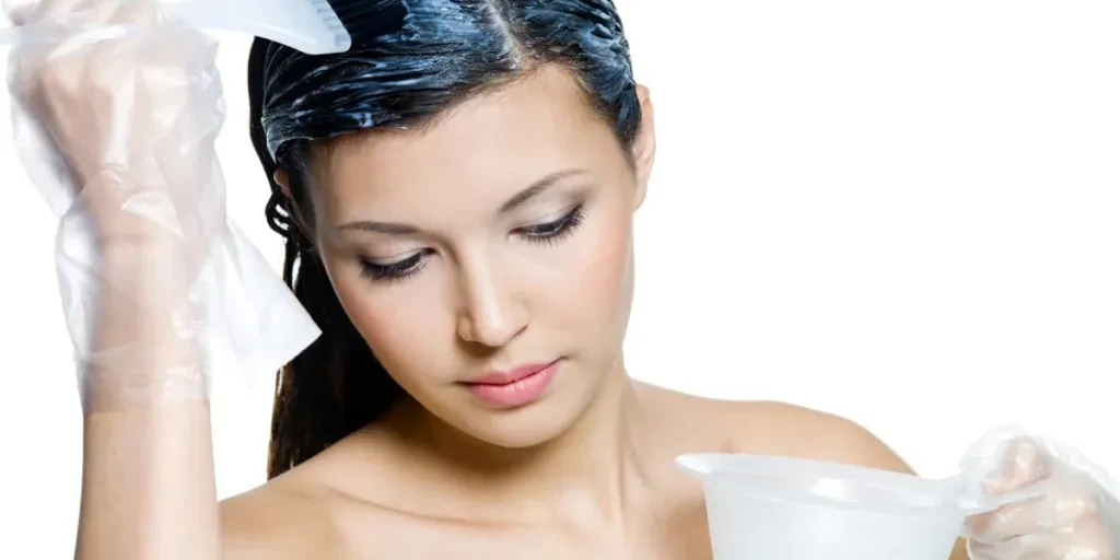 Hermosa mujer tiñéndose el cabello castaño, aislada en blanco