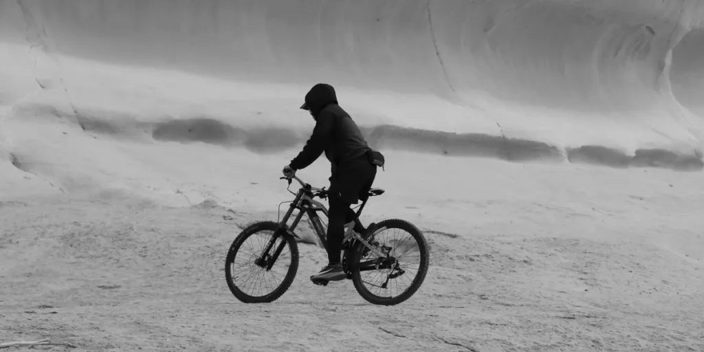 Foto in bianco e nero di un ciclista che naviga in un paesaggio accidentato a Malta. Ideale per temi di avventura e sport