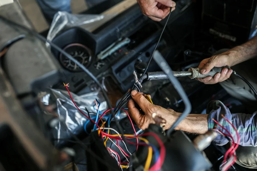 Mecânico de automóveis manuseando fios elétricos