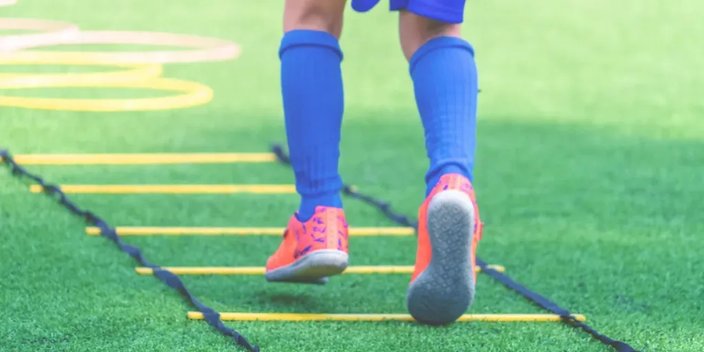 Child feet with soccer boots training on agility speed ladder in soccer training