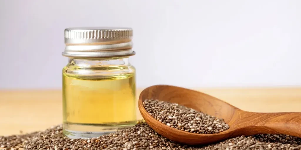 Close up a Chia essential oil and seeds in wooden spoon