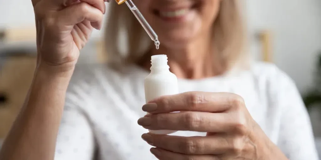 Close-up van een gelukkige oudere vrouw die een fles met essentie opent