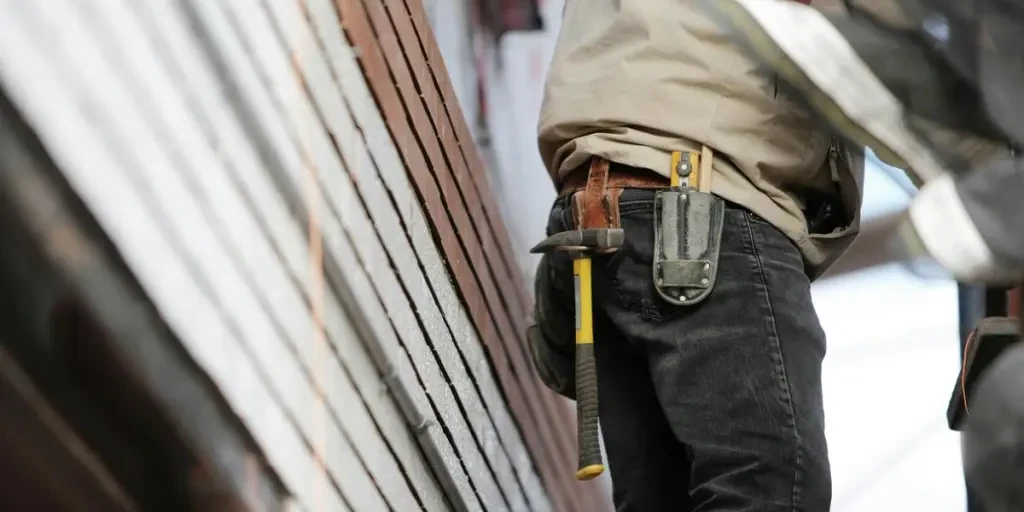 Close-up of a construction worker with hammer and tools, focused on the job