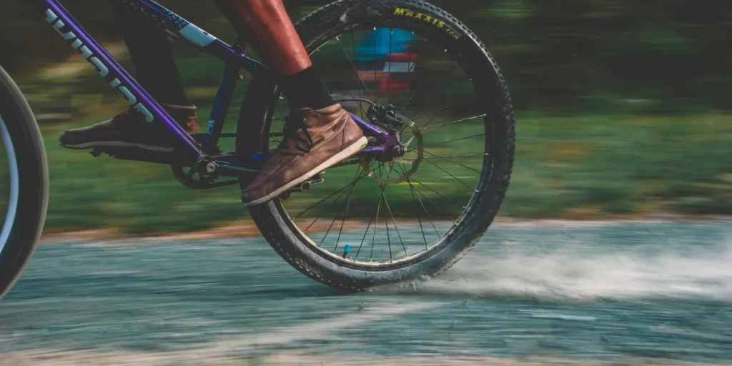 Primo piano di un ciclista di montagna che sfreccia su un sentiero polveroso, mostrando movimento ed eccitazione