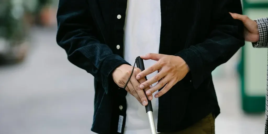 Close-up of a person with visual impairment using a walking stick for guidance outdoors