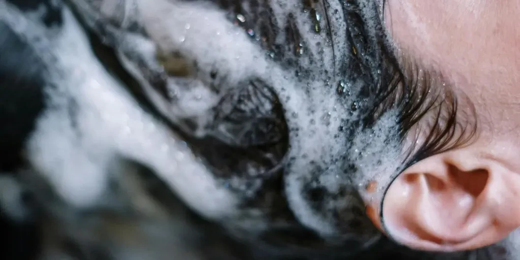 Close-up of a woman getting her hair washed at a salon, covered in shampoo foam