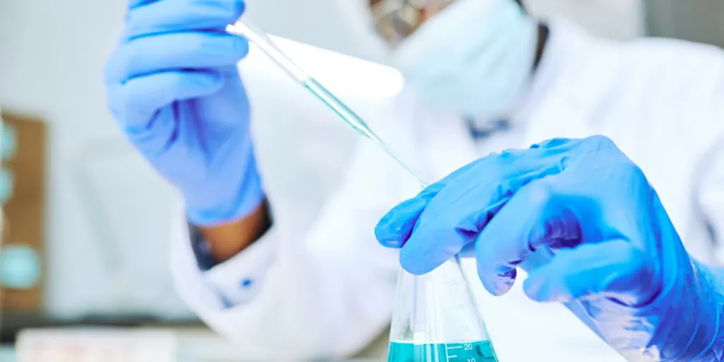 Close up de cientista negro coletando amostras de líquido com pipeta em laboratório,