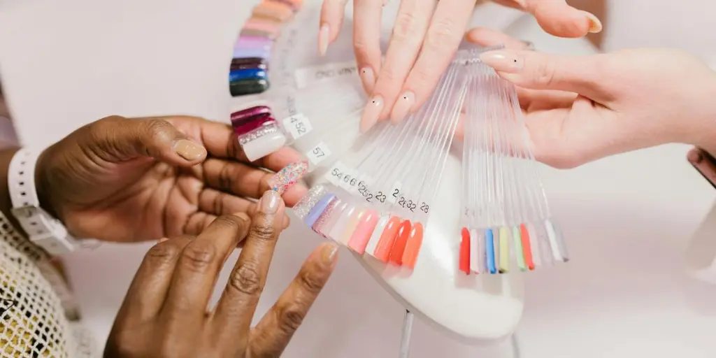 Close-up of hands choosing from a vibrant nail polish sample palette in a salon setting