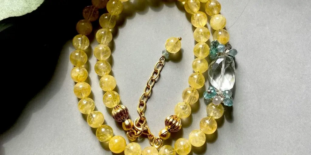 Close-up of shiny yellow beaded jewelry with green eucalyptus leaves