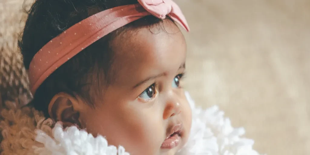 Menina fofa com faixa de cabeça de laço rosa