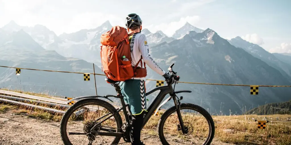 Ciclista con zaino che si gode una vista panoramica sulle montagne a Saas-Fee, Svizzera