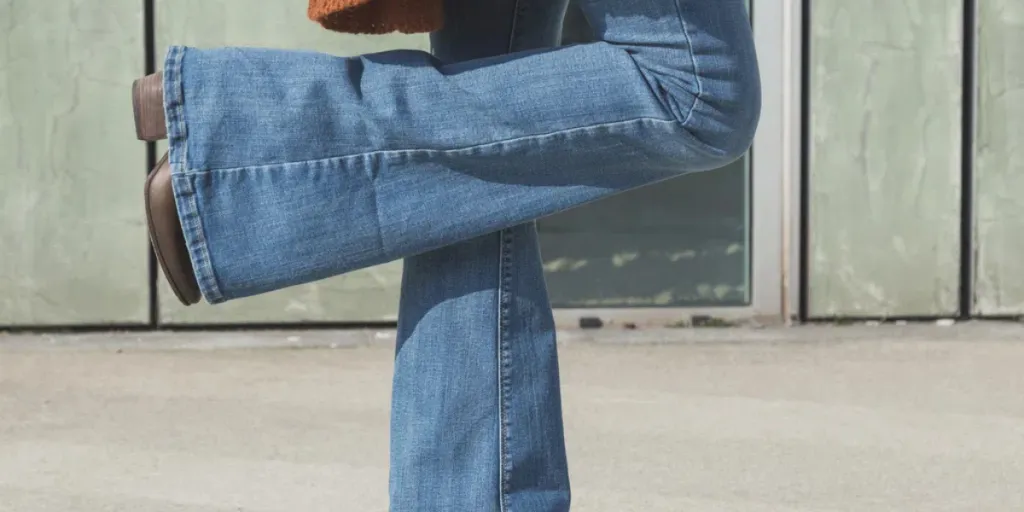 Detalle de una chica con jeans acampanados posando en un contexto urbano