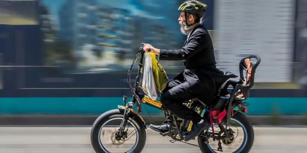 Elderly man with helmet riding an electric bicycle in motion blur. Captures urban lifestyle