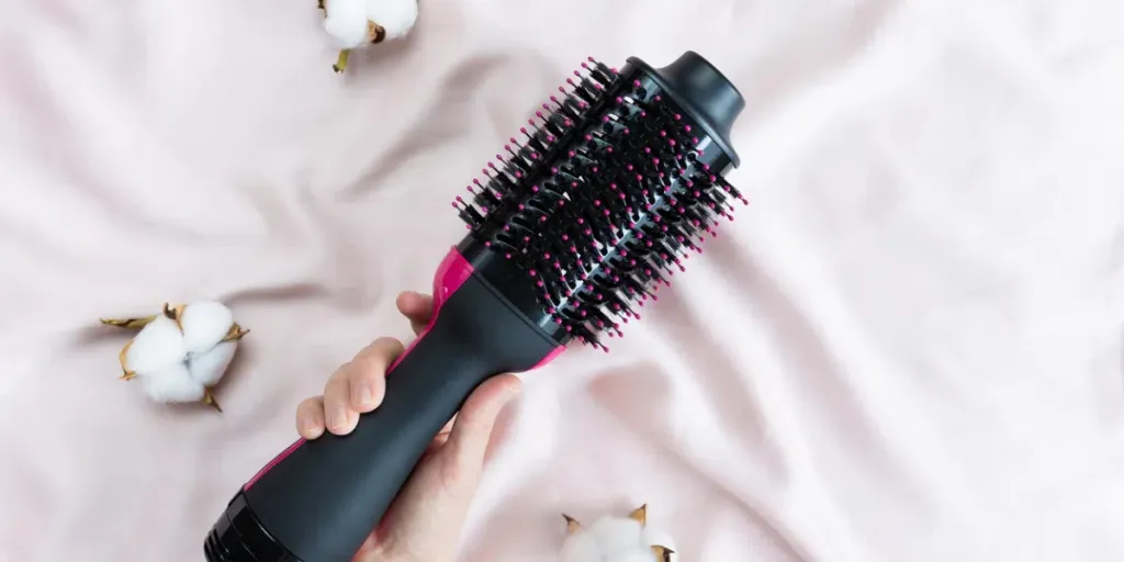 Sèche-cheveux électrique à brosse soufflante sur fond rose