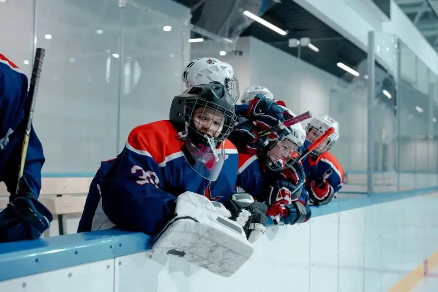 Excited youth ice hockey team celebrating a victory at an indoor arena